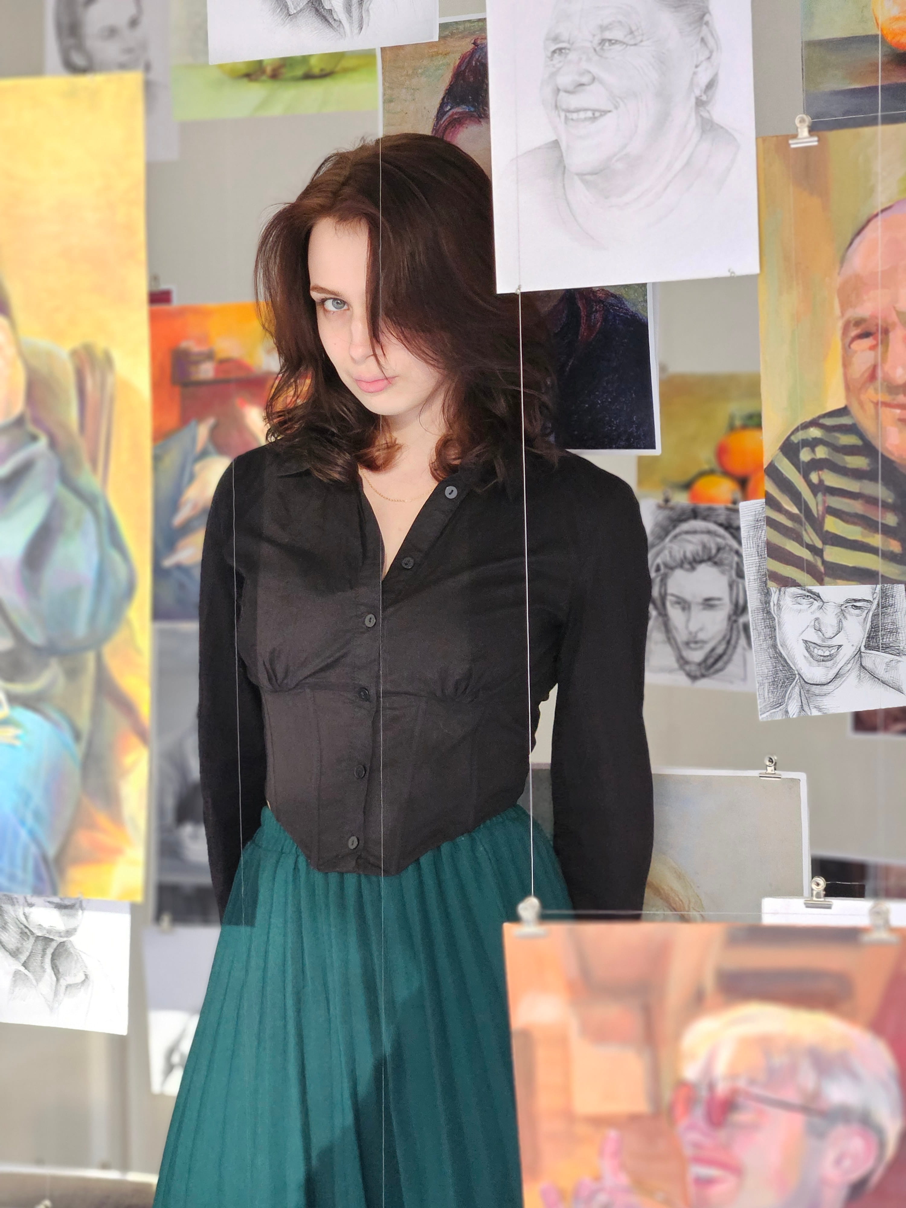 Gabija Malina in her studio, surrounded by portrait paintings and drawings